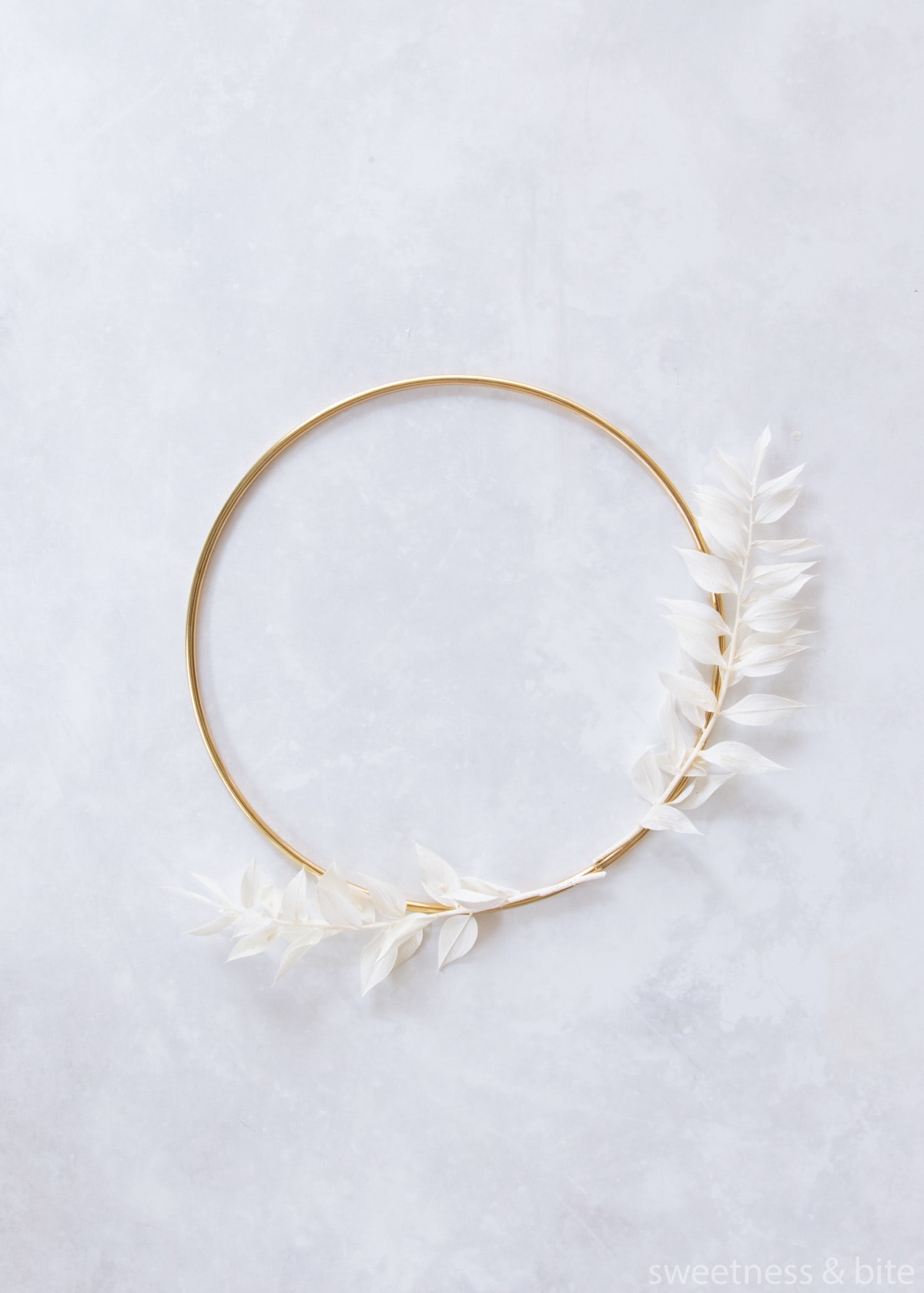 Two pieces of white ruscus tied to the hoop with clear thread.