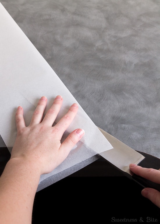 A large knife being used to split the baking paper in half lengthwise.