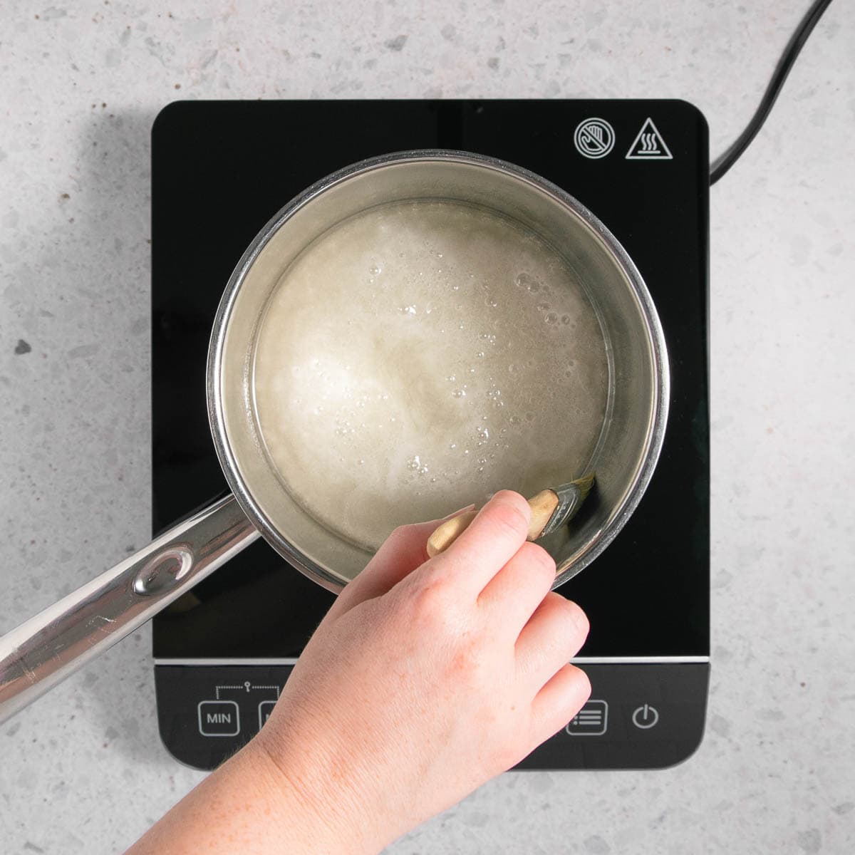 The sugar, water and corn syrup in a stainless steel pan on an induction hot plate.