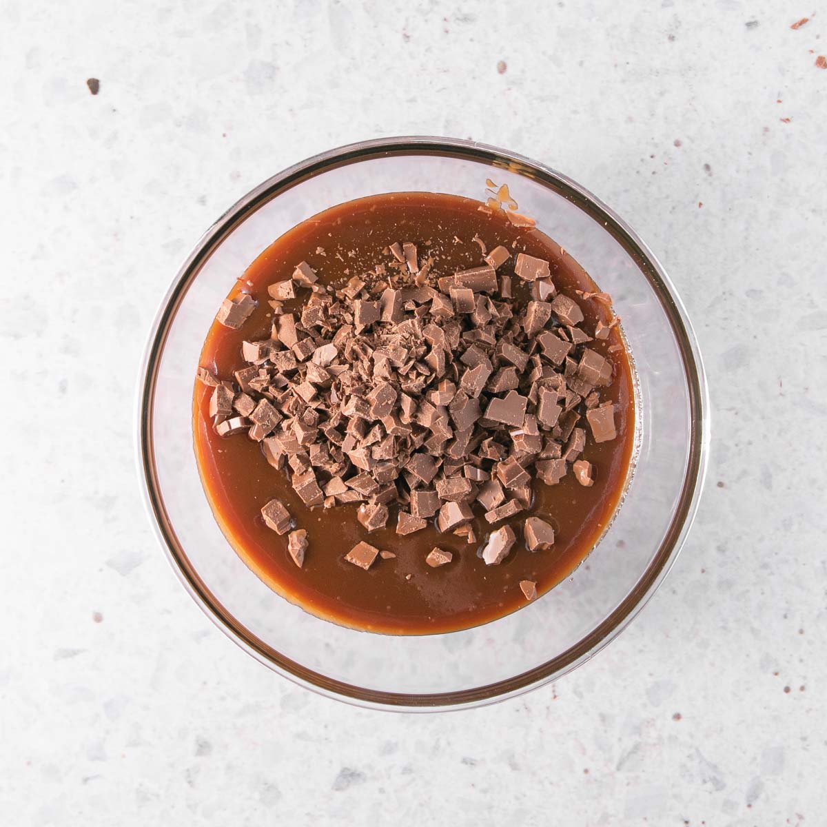 The caramel sauce in a glass bowl, with chopped chocolate sitting on top.