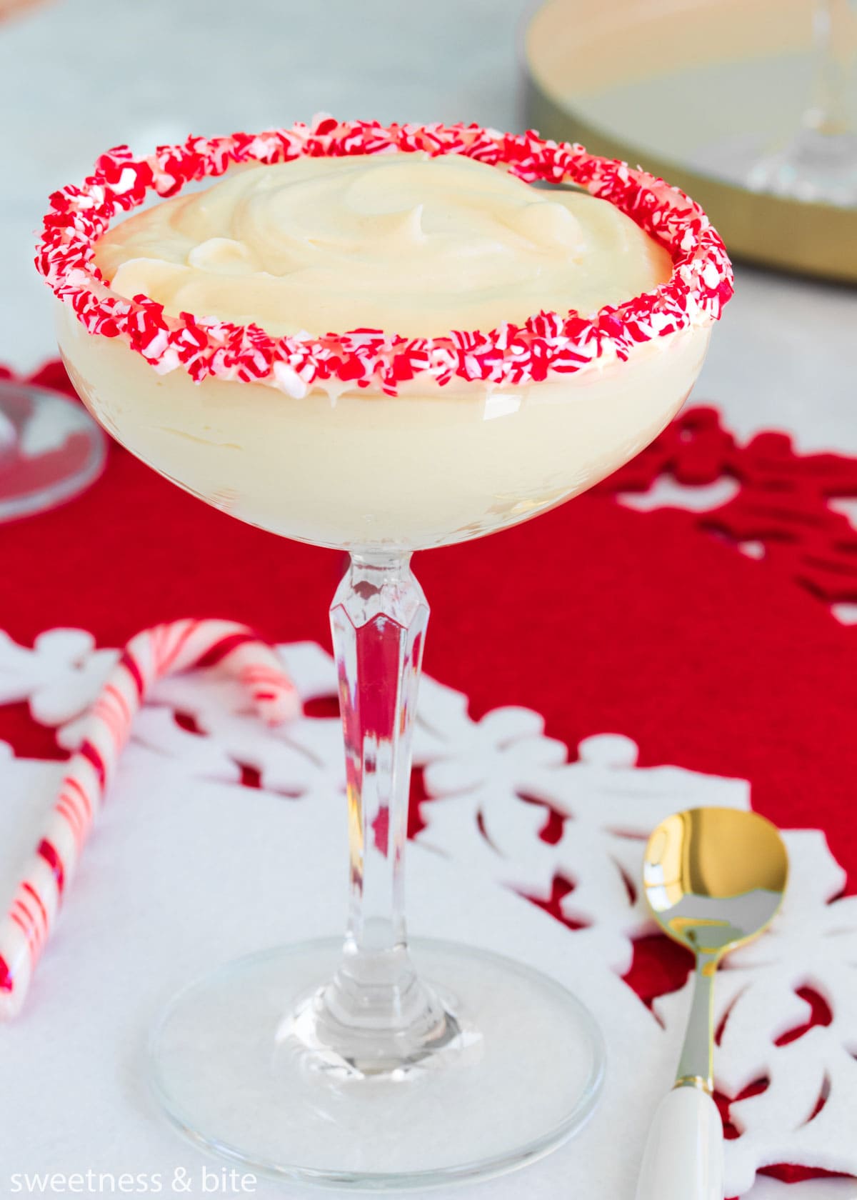 White chocolate peppermint mousse in a stemmed cocktail glass with crushed candy canes around the rim.