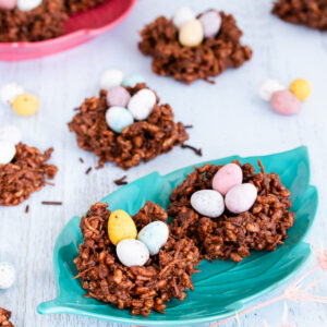 Chocolate Easter nests filled with pastel mini eggs, on a teal green leaf-shaped plate.