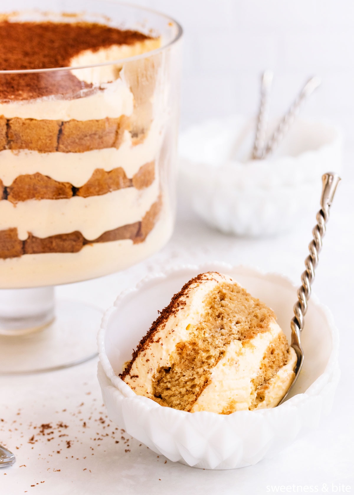 Close-up of spoonful of gluten free tiramisu in a white milk glass bowl.