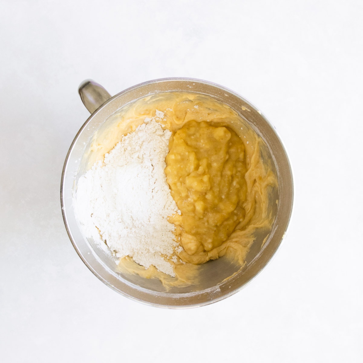 More dry ingredients being added to the bowl with the mashed bananas.