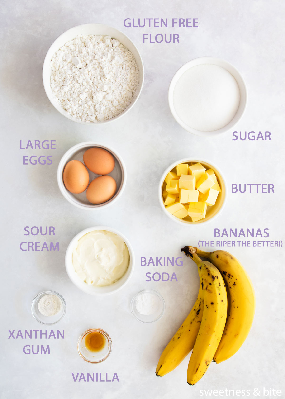 The ingredients for gluten free banana cake in white bowls on a grey background.