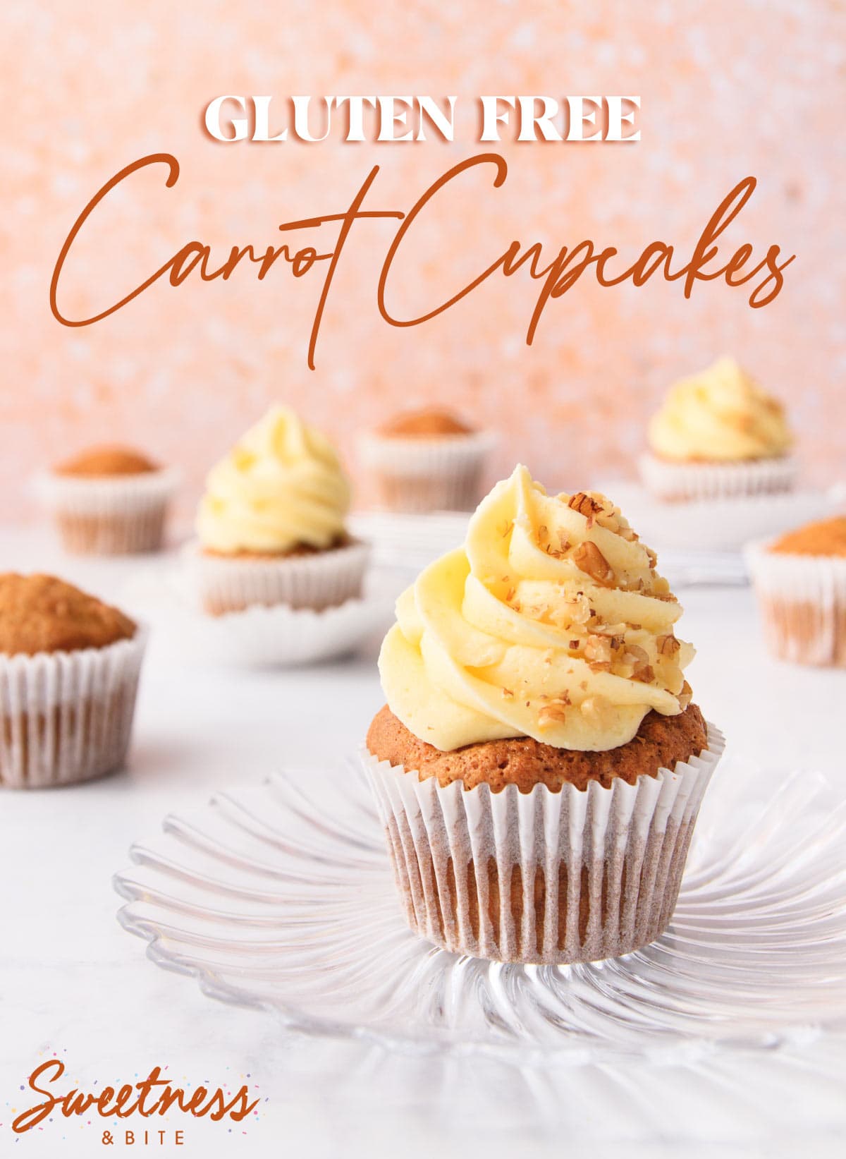 A gluten free carrot cake cupcake with cream cheese frosting on a glass plate, with other cupcakes in the background. 