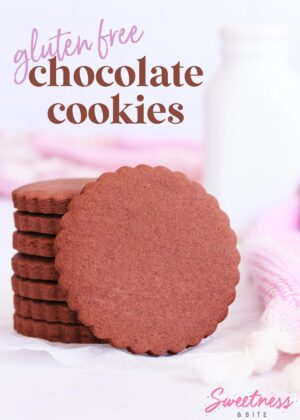 Stack of scalloped-edge round gluten free chocolate cookies, with one cookie resting on its side against the stack.