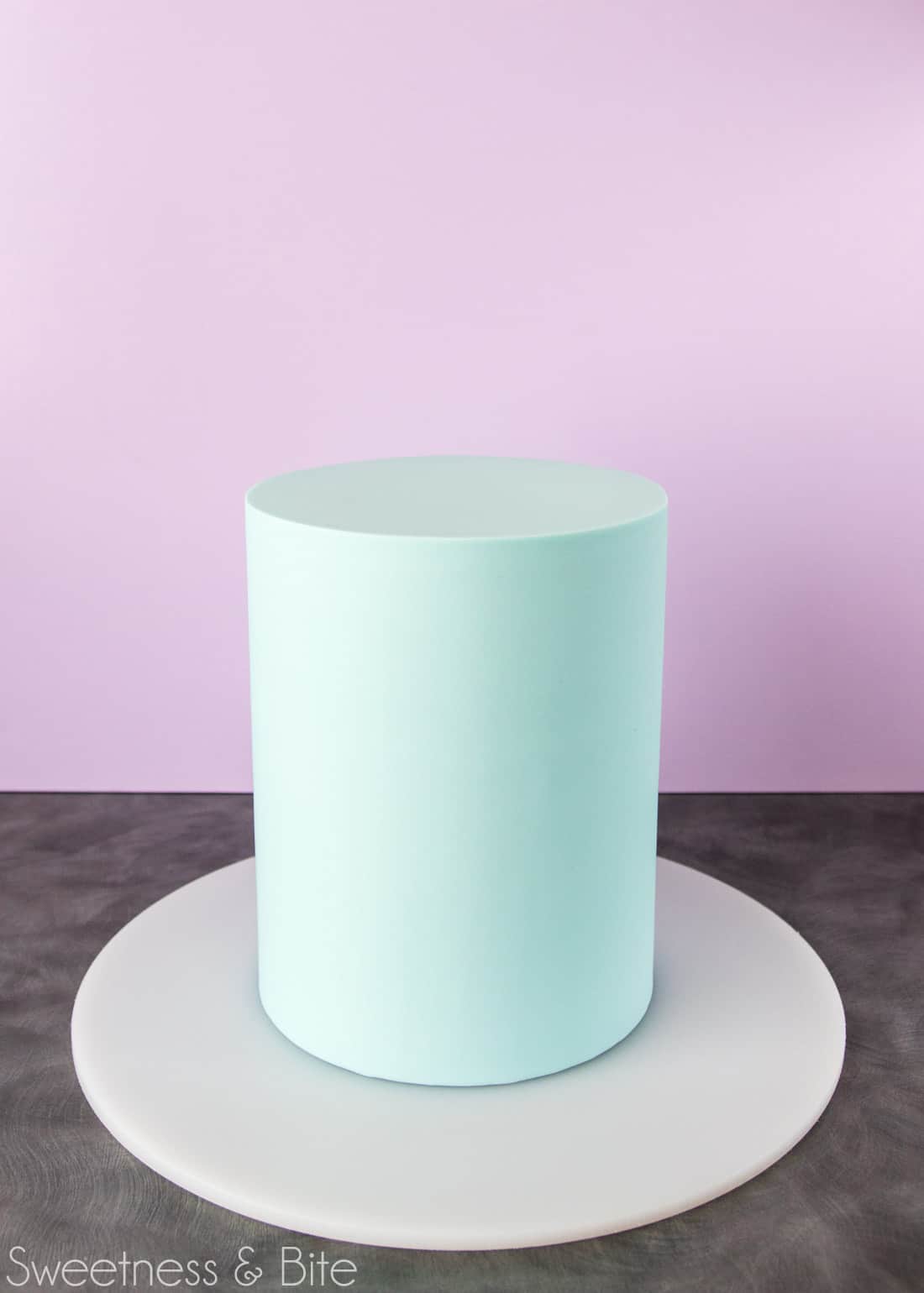 Tall, pale blue fondant covered cake, ready to be painted. 