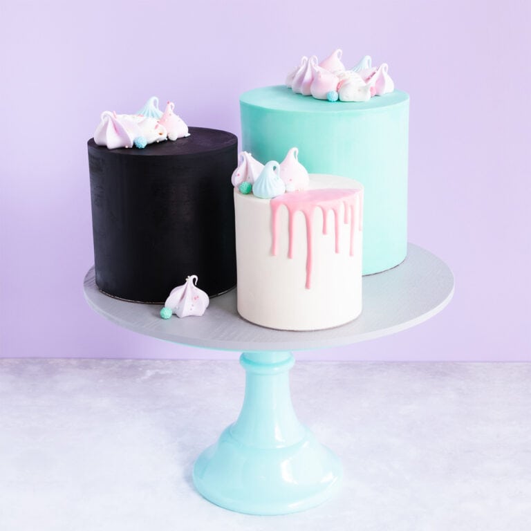 Black, white and teal ganached cakes on a cake stand.