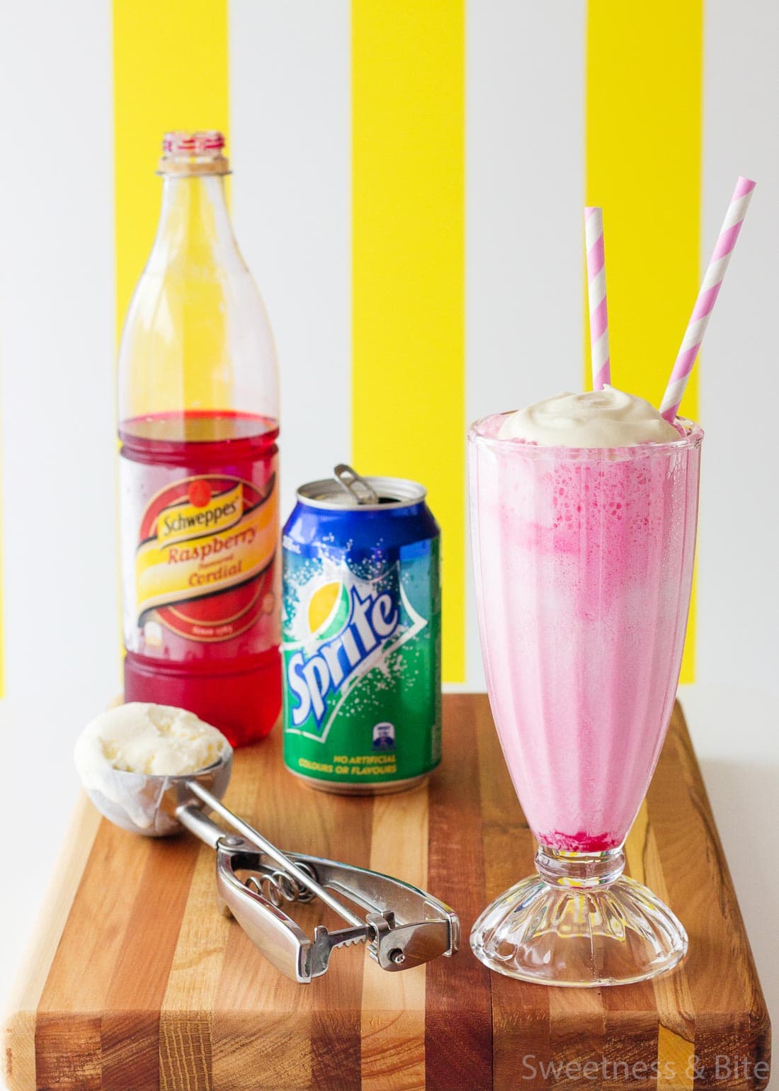 A pink panther drink topped with whipped cream and two pink and white striped straws.