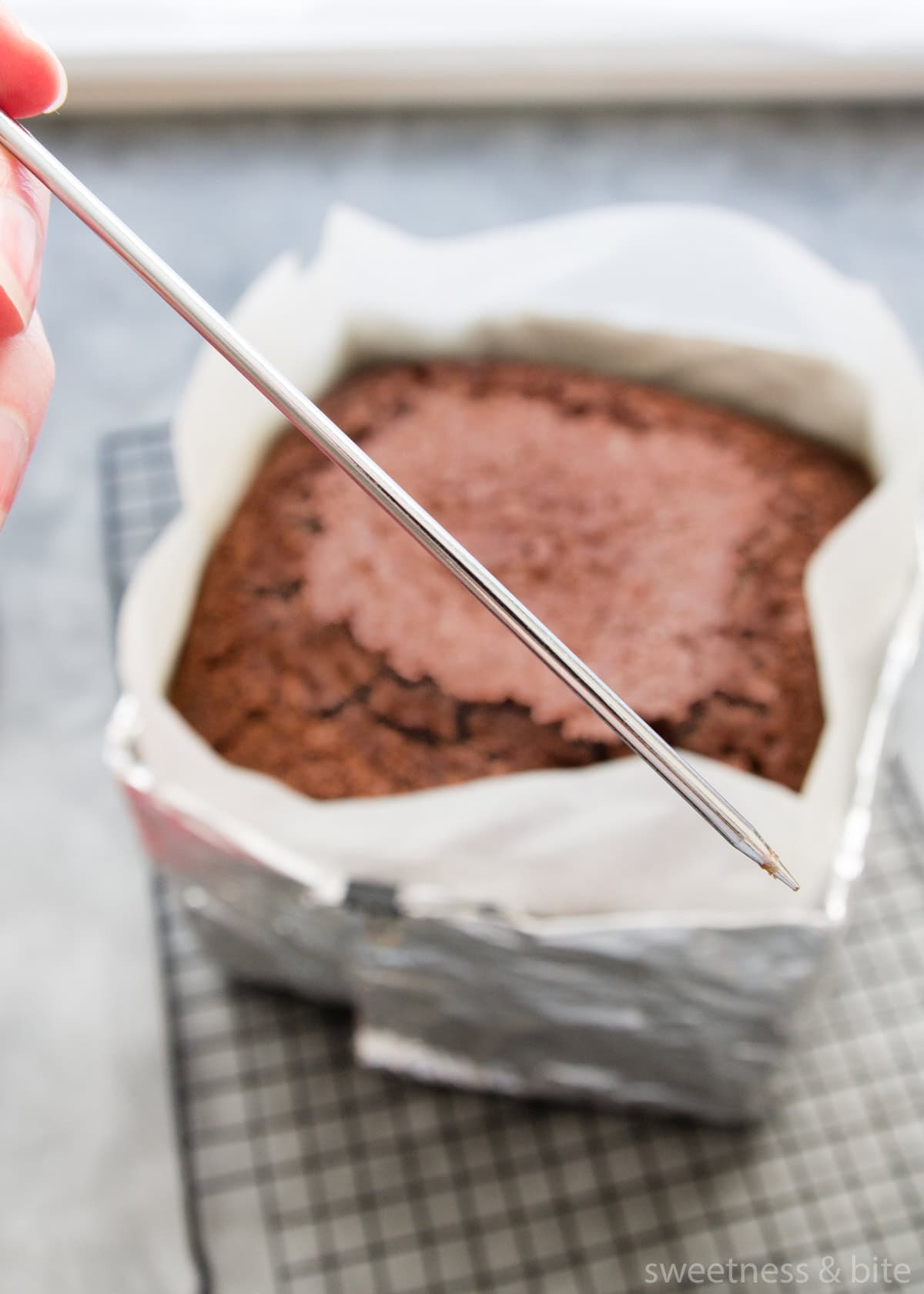 Using a metal skewer to check if a chocolate cake is done.