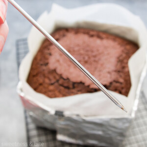 A skewer being used to check whether a chocolate cake is done.