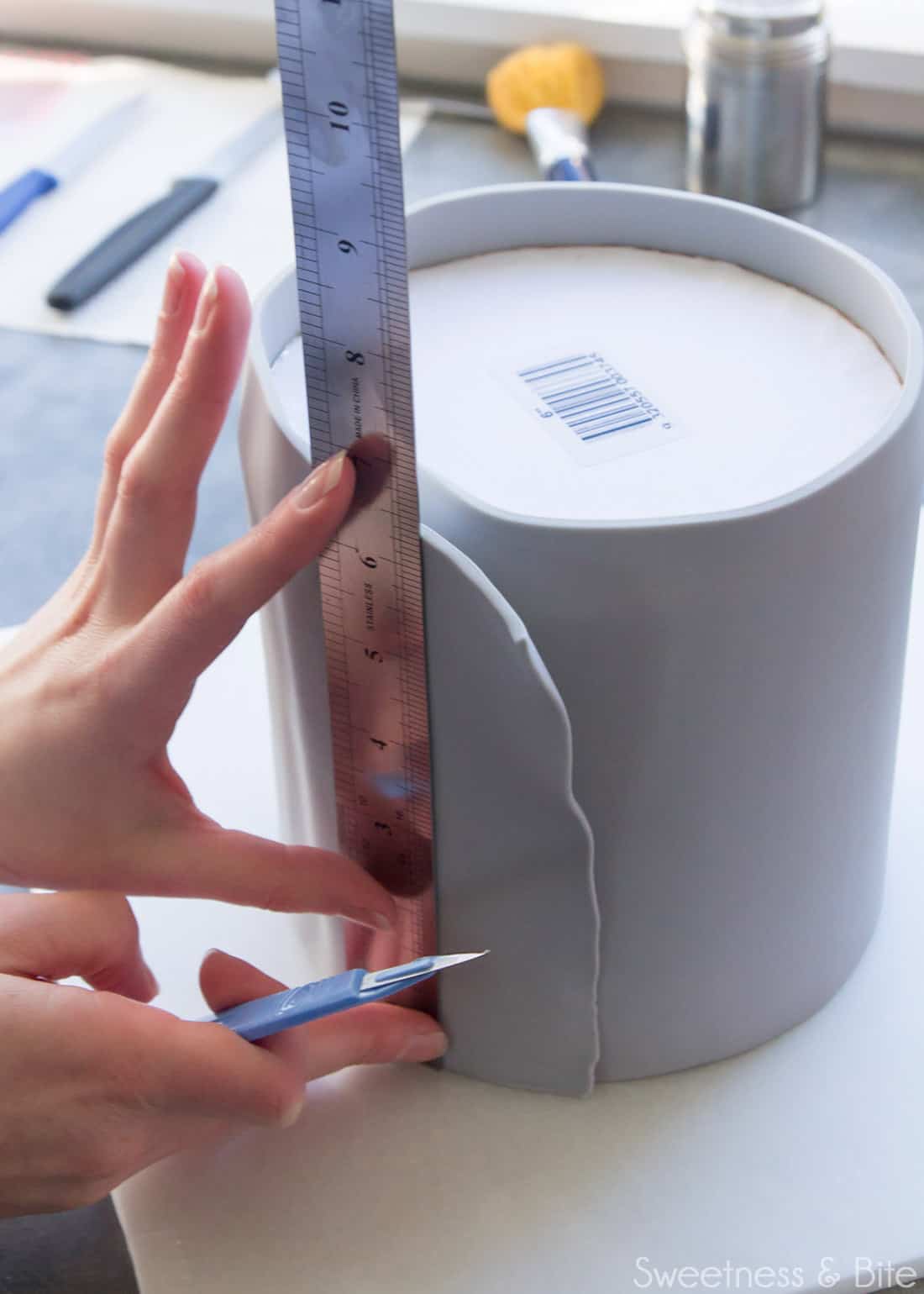 A ruler being held against the cake where the fondant overlaps.