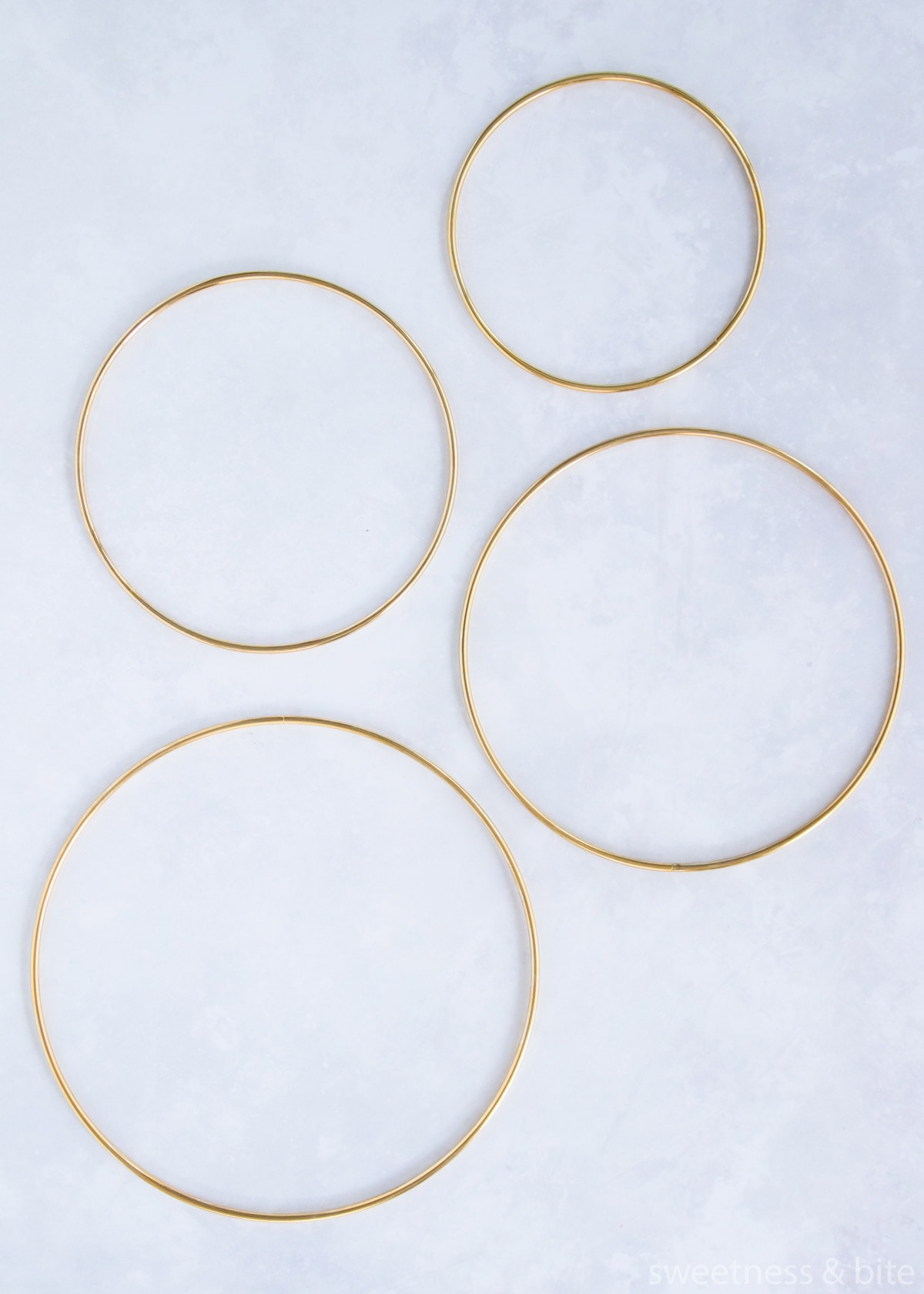 Four gold coloured metal craft hoops of varying sizes.