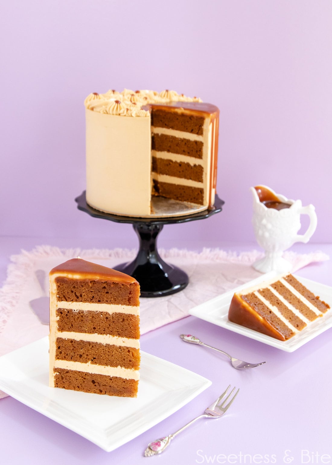 Slice of cake showing the layers of cake and caramel buttercream. Cake on the cake stand in the background.