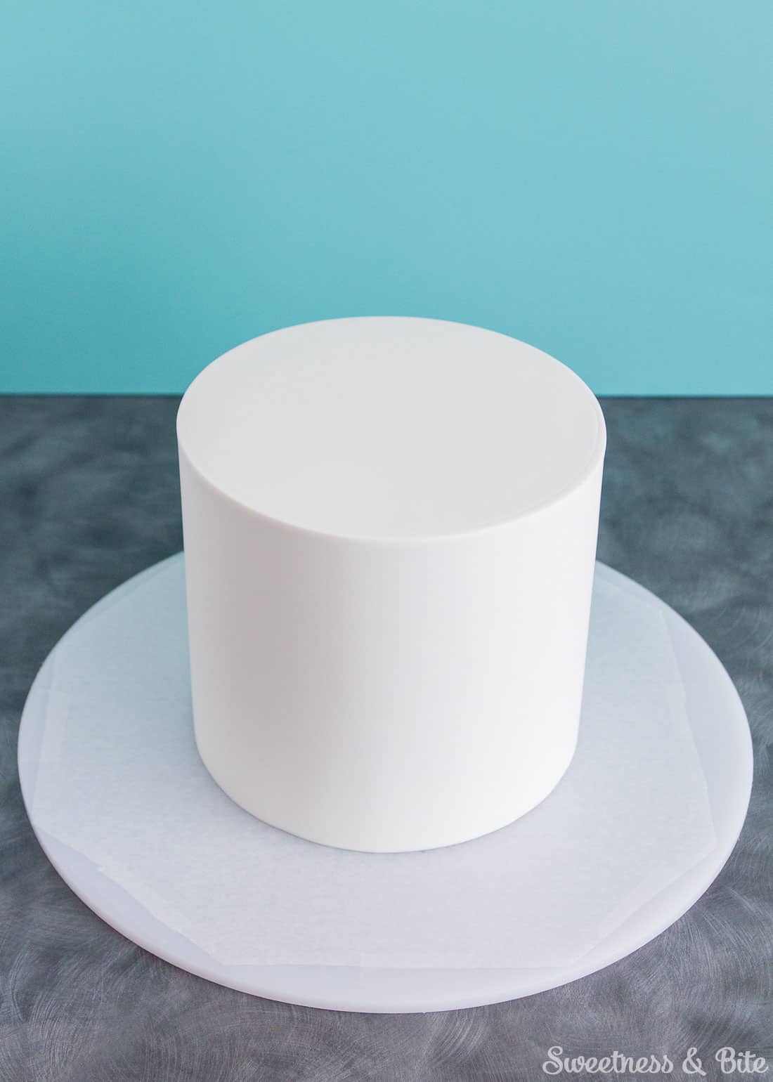 A six inch round cake covered in white fondant icing.