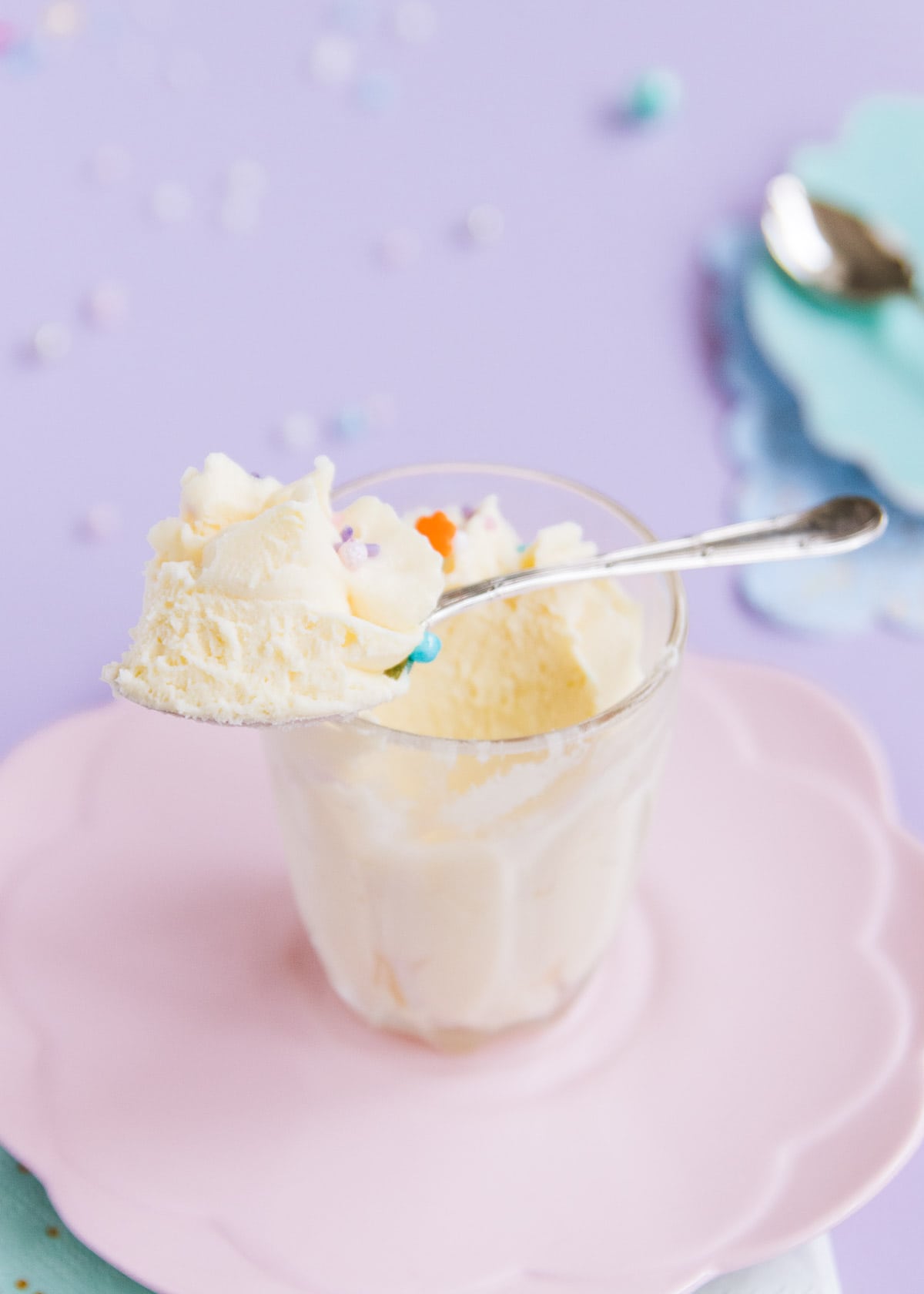 A small glass of white chocolate mousse, with a spoonful resting on the rim. 