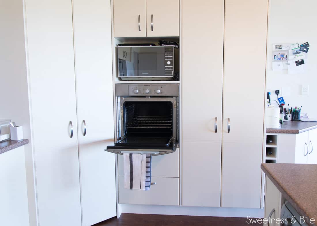 Beige cabinetry with a very small in-built wall oven.