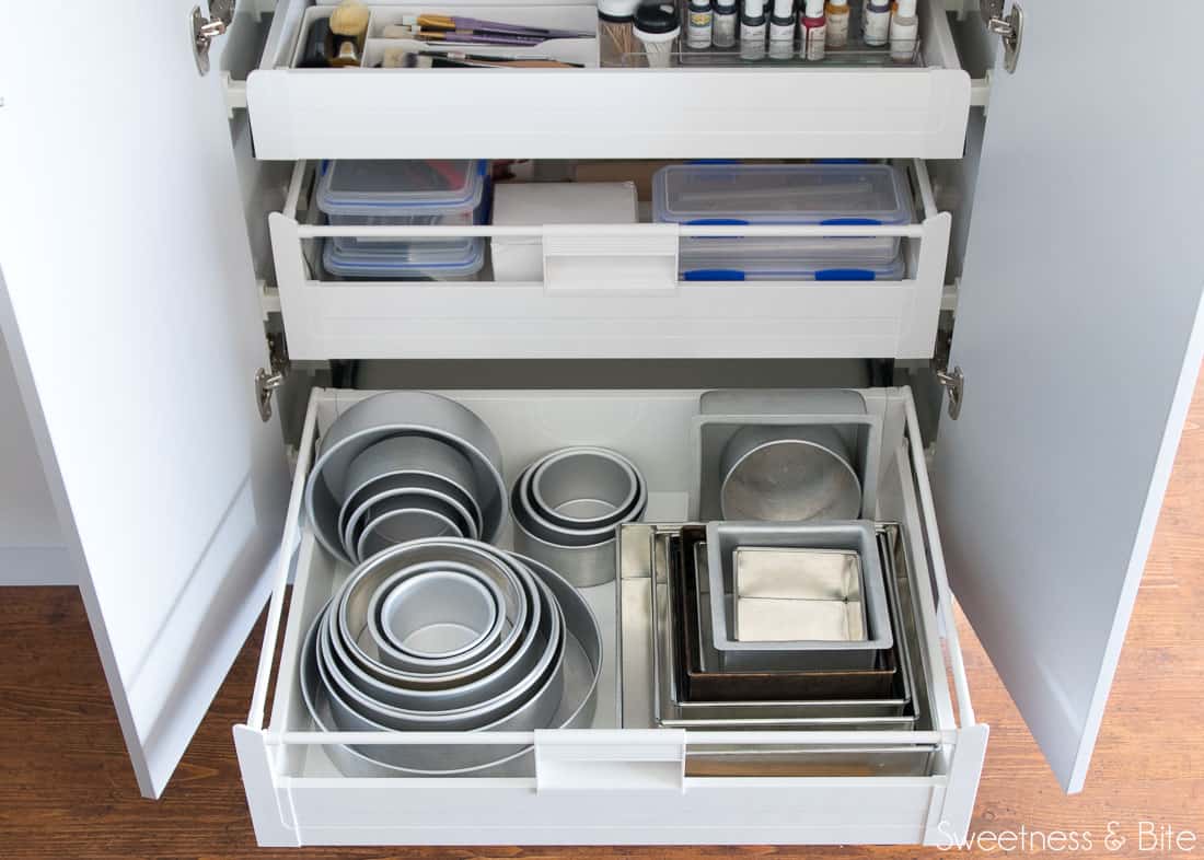 The lower drawer, filled with nested round and square cake pans in varying sizes. 